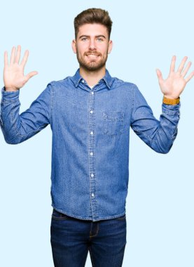 Genç yakışıklı sarışın adam gösteren ve parmak sayısı on ile işaret rahat denim gömlek giyen emin ve mutlu gülümseyen.