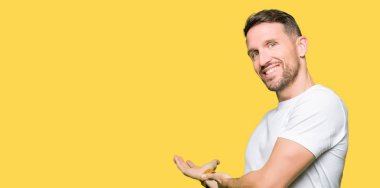 Açık el ile doğal gülümseyen girmek için rahat beyaz t-shirt davetkar giyen yakışıklı adam