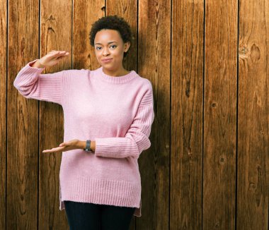 Güzel genç Afro-Amerikan kadın ile büyük ve büyük boy işaret, ölçü birimi sembol gösteren el eller izole arka plan yüzünden. Kameraya bakarak gülümsüyordu. Ölçüm kavramı.