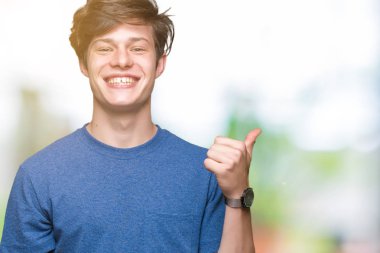 Hareketi el ile mutlu yaşasın yapıyor izole arka plan üzerinde mavi t-shirt giyen genç yakışıklı adam. Başarı gösteren kameraya bakarak ifade onaylama.