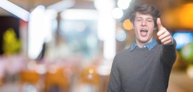 Genç yakışıklı zarif adam gösterilen ve kendinden emin ve mutlu gülümseyen bir parmak ile işaret eden oktan yukarı izole arka plan üzerinde.