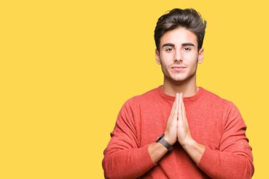 Yakışıklı delikanlı birlikte emin gülümseyen bağışlanmak ellerle dua izole arka plan üzerinde.