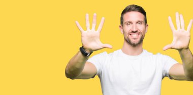 Yakışıklı adam gösterilen ve parmakları ile işaret casual beyaz t-shirt giyen kendinden emin ve mutlu gülümseyerek süre on numara.