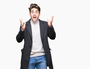 Üzerinde kış ceket giyen genç zarif adam deli kutluyor arka plan izole ve başarı için kaldırdı kollarını açarak hayrete ve heyecanlı çığlık gözleri açık. Kazanan kavramı