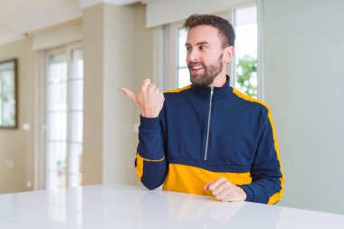 Yakışıklı adam evde mutlu yüz bakarak gülümseyen ve başparmak ile yan işaret.