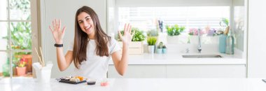 Güzel genç kadının teslimat gösteren ve parmaklar numarası on ile işaret yukarı gelen Asya Suşi yeme geniş açı resmi emin ve mutlu gülümseyen.