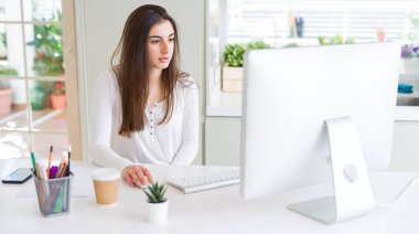 Bilgisayar kullanarak çalışan güzel genç iş kadını, gülümseyen ve online çalışma üzerinde konsantre