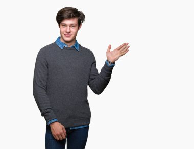 Genç yakışıklı zarif adam neşeli sunulması ve kameraya bakarak avucunun ile işaret gülümseyen izole arka plan üzerinde.