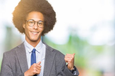 Afro saç giyen ile genç Afro-Amerikalı iş adamı arkasından el ve kadar başparmak ile işaret emin gülümseyen gözlük