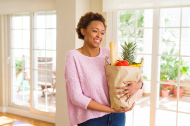 Kağıt torba dolu tutan genç güzel Afrikalı-Amerikalı kadın