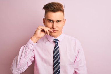 Genç yakışıklı işadamı gömlek giyen ve izole pembe arka plan ağız ve dudakları parmakları ile zip olarak kapalı dudaklar üzerinde duran kravat. Gizli ve sessiz, tabu konuşma
