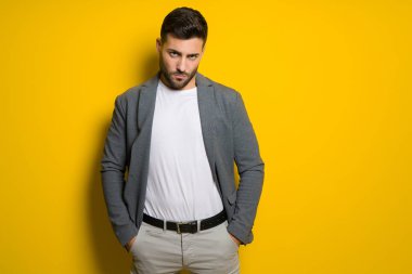 Genç yakışıklı adam possing ve modelleme sarı izole bac üzerinde