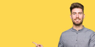 Kameraya bakarak yan el ve parmak ile işaret eden genç yakışıklı iş casual adam yüzünde kocaman bir gülümseme ile.