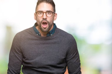 Korkuyor ve şok sürpriz ifade, korku ve heyecan yüz ile izole arka plan üzerinde gözlük takan genç yakışıklı adam.