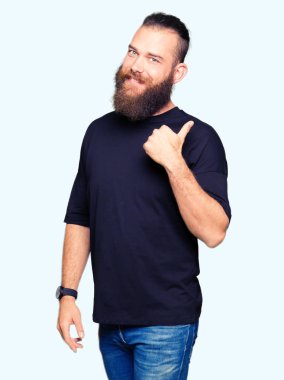 Mutlu yüz görünümlü ve başparmak yukarı ile yan işaret gülümseyen rahat t-shirt giyen genç sarışın adam.