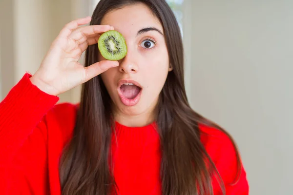 驚きの顔でショックで恐怖を感じ 恐怖表現で興奮した半分の新鮮な緑のキウイを食べる美しい若い女性 — ストック写真