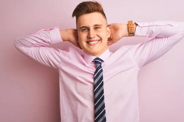 年轻英俊的商人穿着衬衫和领带站在孤立的粉红色背景放松和伸展 手臂和手后头和脖子微笑快乐 — 图库照片
