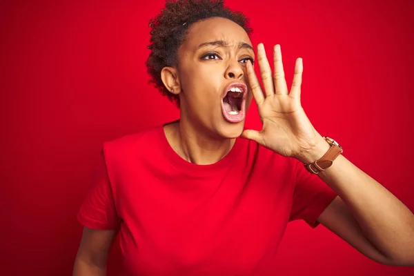 孤立した赤い背景の上にアフロの髪を持つ若い美しいアフリカ系アメリカ人女性は 口の上に手で大声で叫んで叫びました コミュニケーションコンセプト — ストック写真