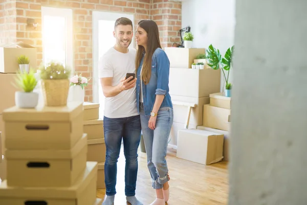 Casal Jovem Mudando Para Uma Nova Casa Usando Smartphone Sorrindo — Fotografia de Stock