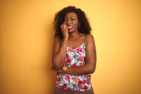 孤立した黄色の背景の上に花の夏のTシャツを着ているアフリカ系アメリカ人の女性は 口を噛む爪に手を当て ストレスと緊張を見ています 不安の問題 — ストック写真