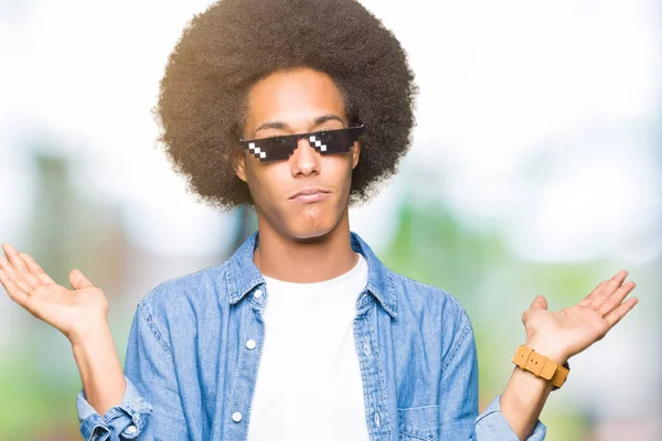 非洲青年美国人与非洲头发穿着暴徒生活眼镜无线索和混乱的表情与手臂和手抬起来 怀疑概念 — 图库照片