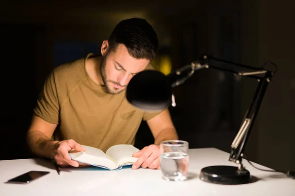 Giovane bell'uomo che studia a casa, che legge un libro di notte — Foto Stock