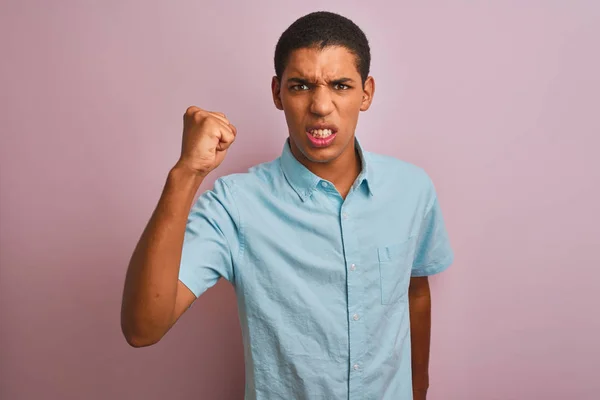 年轻的英俊阿拉伯男子穿着蓝色衬衫站在孤立的粉红色背景愤怒和疯狂的提高拳头沮丧和愤怒 而愤怒地喊道 愤怒和侵略性的概念 — 图库照片