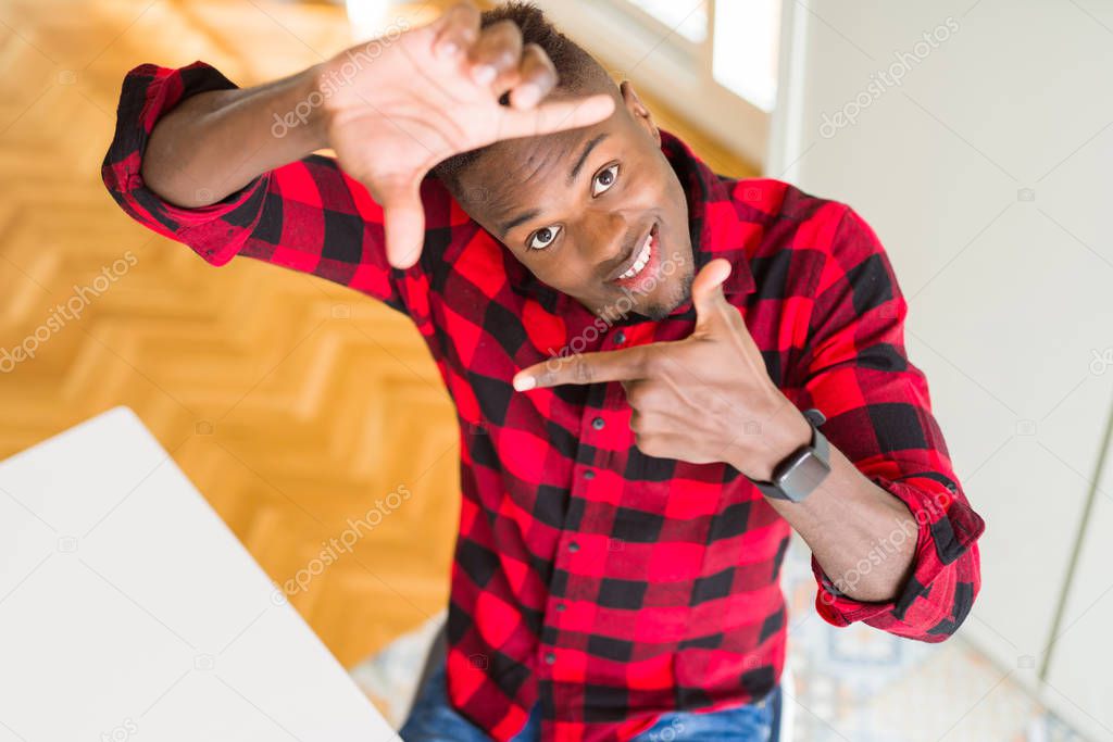 Overhead angle of handsome african american man smiling making frame with hands and fingers with happy face. Creativity and photography concept.