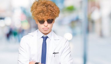 Profesyonel ceket ve güneş gözlüğü şüpheci ve sinir giyen genç yakışıklı bilim adamı, kesişmiş kollar ile yüz üzerindeki ifade onaylanmaya. Negatif kişi.