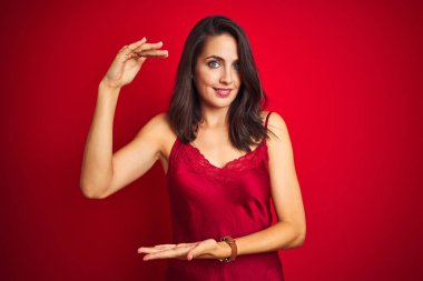 Genç güzel kadın büyük ve büyük boy işareti, ölçmek sembolü gösteren eller ile kırmızı izole arka plan üzerinde seksi iç çamaşırı giyiyor. Kameraya bakarak gülümsüyor. Ölçme konsepti.