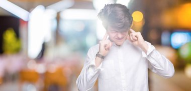 Yüksek sesle müzik gürültü rahatsız ifade parmaklarıyla kulaklarıyla kapsayan izole arka plan üzerinde genç yakışıklı iş adamı. Sağır kavramı.