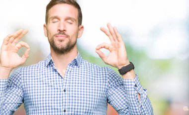 Mavi gözlü yakışıklı iş adamı rahatla ve gülümseyen gözlerle kapalı parmak jestle meditasyon yapıyor. Yoga kavramı.