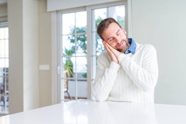 Rahat kazak giyen yakışıklı adam yorgun rüya uyku ve kapalı gözlerle gülümseyerek birlikte elleri ile poz.