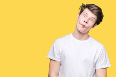 İzole arka plan yapma balık yüzüne dudaklı, çılgın ve komik bir jest Casual beyaz t-shirt giyen genç yakışıklı adam. Komik ifade.