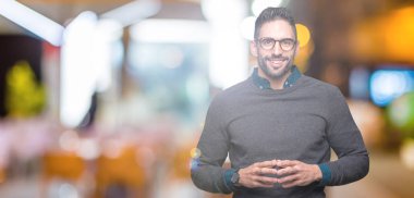 Arka plan eller üzerinde gözlük takan genç yakışıklı adam birlikte izole ve rahat ve neşeli gülümseyen parmak çarpı işareti. Başarı ve iyimser