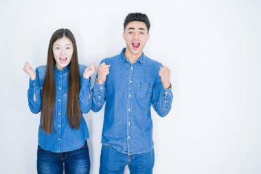 Beyaz izole arka plan üzerinde güzel genç Asya çift sürpriz kutluyor ve başarı için hayran silah kaldırdı ve açık gözleri ile. Kazanan kavramı.