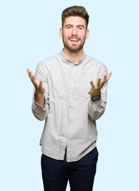 Genç ve yakışıklı bir adam gündelik gömlek giyip çılgınlığı kutluyor ve başarıya hayret ediyor kolları açık ve gözleri açık heyecanla haykırıyor. Kazanan konsept