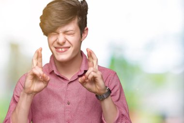 Genç yakışıklı iş adamı geçiş parmakları umut ve gözleri kapalı ile gülümseyen izole arka plan üzerinde. Şans ve batıl kavramı.