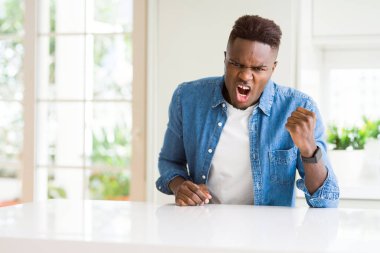 Yakışıklı afro-amerikan adam evde kızgın ve deli yükselterek yumruk sinirli ve öfkeli öfke ile bağırırken. Öfke ve agresif kavram.