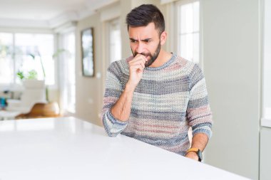 Evde rahat kazak giyen yakışıklı İspanyol adam vurguladı ve ağız ısırma çivi elleri ile gergin bakıyor. Anksiyete sorunu.