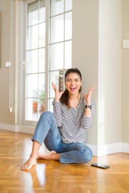 Evde katta oturan genç güzel kadın deli ve çığlık kaldırdı ve kapalı gözleri heyecanlı silah ile başarı için deli kutluyor. Kazanan kavramı