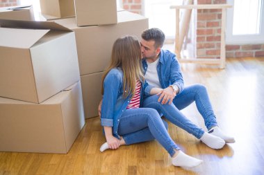 Yeni eve hareket aşk genç güzel çift, karton kutular etrafında yeni daire için çok mutlu ve neşeli yerde oturuyor