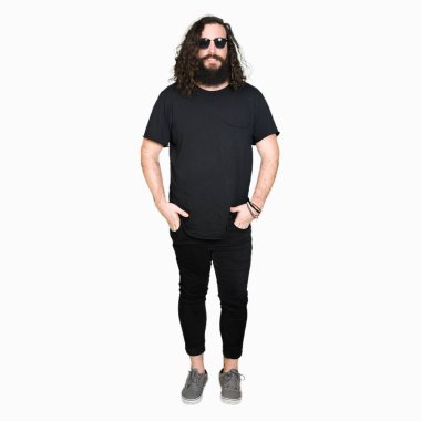 Genç hipster adamla uzun saç ve sakal yüzünde mutlu ve güzel bir gülümseme ile güneş gözlüğü takıyor. Şanslı kişi.