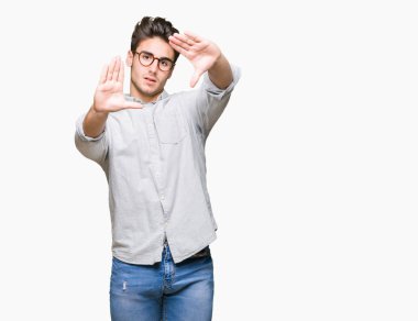Genç yakışıklı adam gözlük izole üzerinde çerçeve kullanarak el avuç içi ve parmaklar, kamera perspektif yapıyor gülen arka plan
