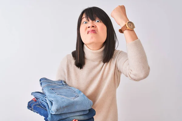 孤立した白い背景の上に折り畳まれたジーンズを持つ美しい中国の店主の女性は 狂気と怒りで叫んでイライラし 怒りの概念 — ストック写真