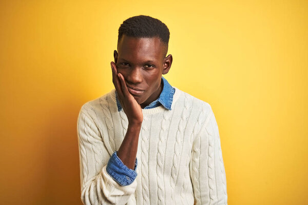 African american man wearing denim shirt and white sweater over isolated yellow background thinking looking tired and bored with depression problems with crossed arms.
