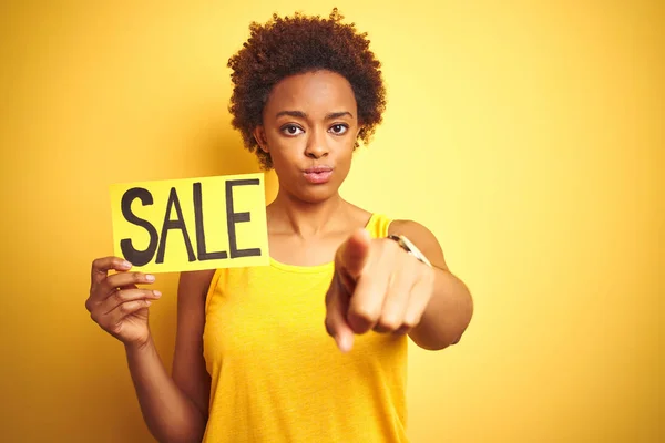 アフリカ系アメリカ人女性は カメラに指で指で指を指し示す黄色の孤立した背景の上に販売ボードを保持し 手のサイン 正面から肯定的で自信のあるジェスチャー — ストック写真