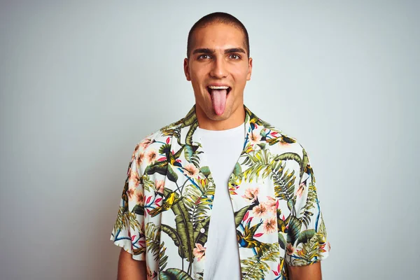 年轻的帅哥在假期穿着夏威夷衬衫在白色背景坚持舌头与有趣的表情高兴 情感概念 — 图库照片