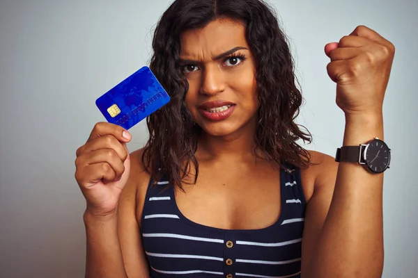 Transsexual transgender customer woman holding credit card over isolated white background annoyed and frustrated shouting with anger, crazy and yelling with raised hand, anger concept