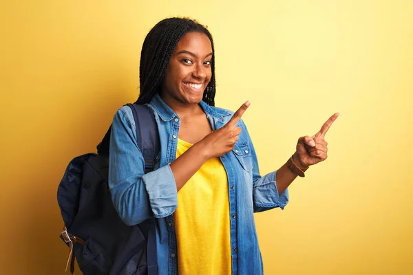 아프리카 미국인 여학생 배낭을 웃으며 손가락을 좌우로 향하고 카메라를 바라본다 — 스톡 사진